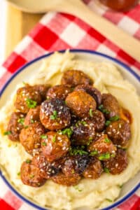 “Baked honey garlic meatballs in a glossy, sticky sauce garnished with sesame seeds and green onions”