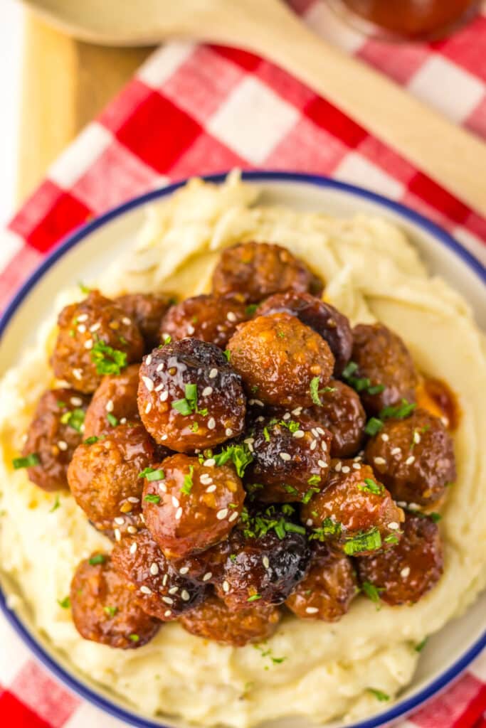 “Baked honey garlic meatballs in a glossy, sticky sauce garnished with sesame seeds and green onions”
