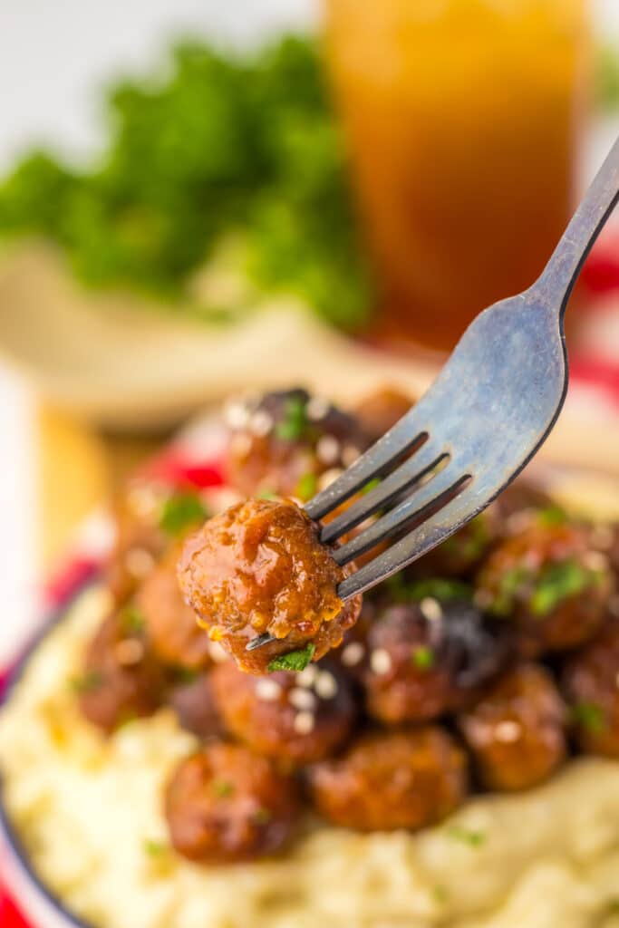 “Baked honey garlic meatballs in a glossy, sticky sauce garnished with sesame seeds and green onions”