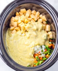 Top-down view of thick creamy pot pie filling with corn and peas before adding biscuits.