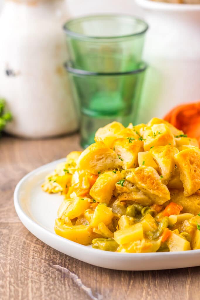 Close-up of biscuit-topped chicken pot pie casserole served with carrots and peas.