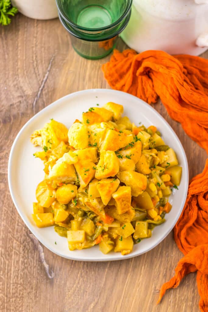 Styled plate of chicken pot pie casserole with green drinkware and a orange napkin.