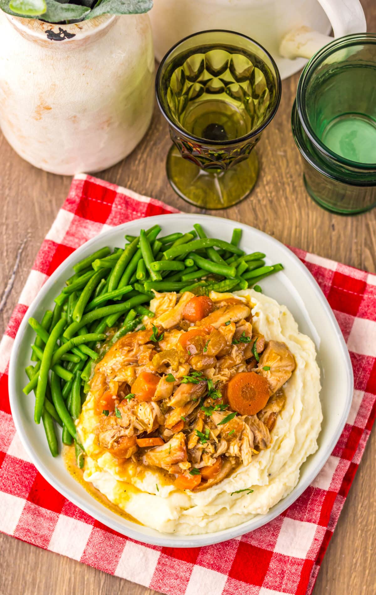 Chicken pot roast dinner with carrots, potatoes, and green beans served on a white plate