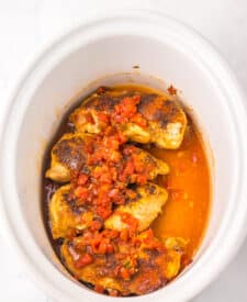 Cooked Monterey Chicken topped with BBQ sauce and tomatoes in white dish