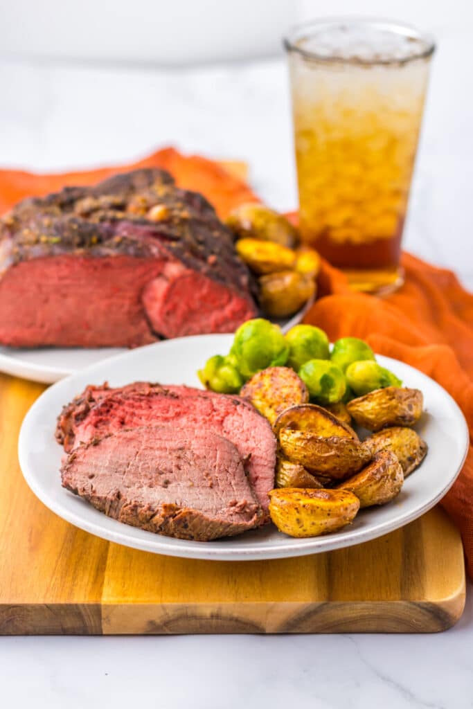 Thick slices of prime rib roast with roasted potatoes on white plate