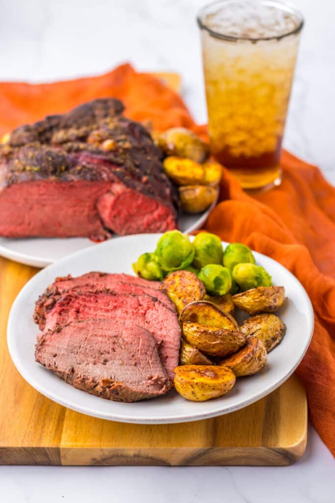 Thick slices of prime rib roast with roasted potatoes on white plate