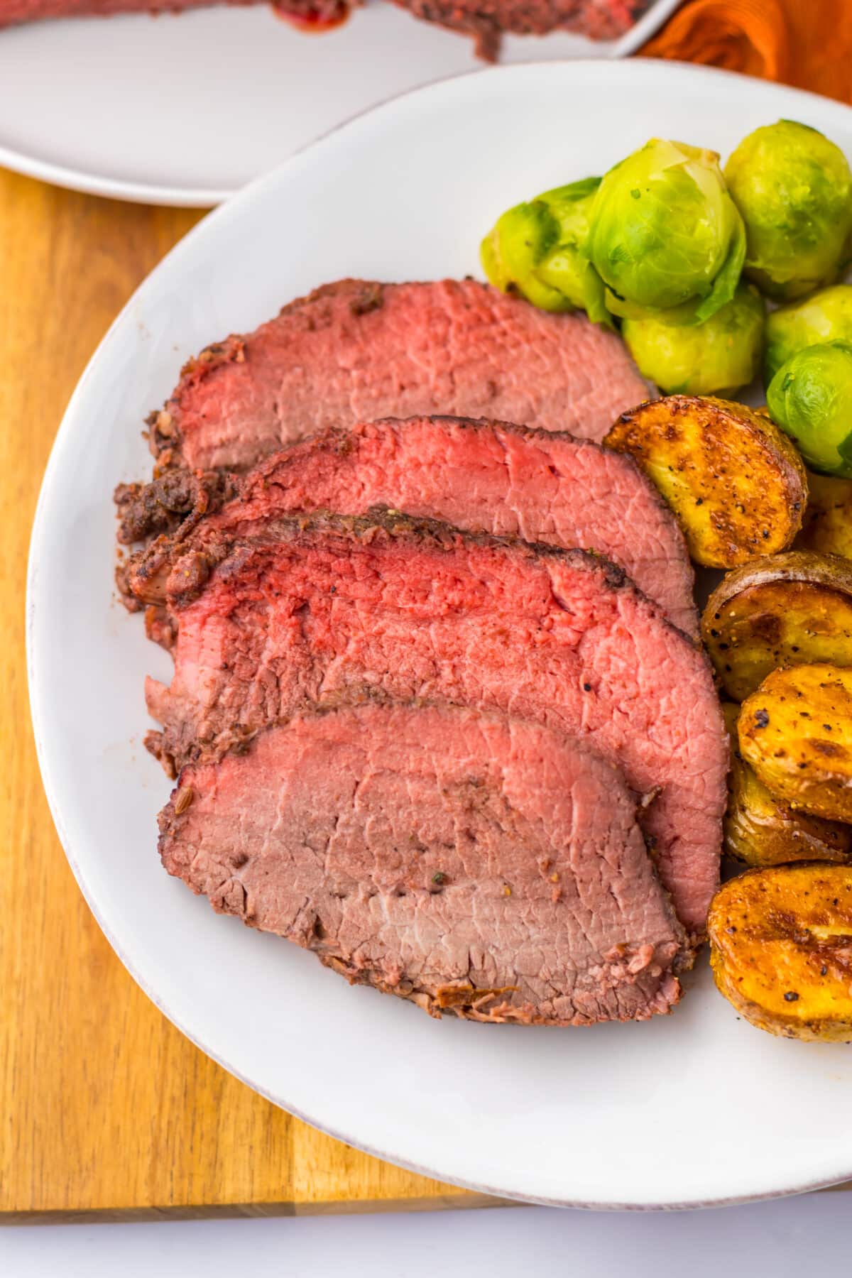 Thick slices of prime rib roast with roasted potatoes on white plate