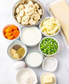 Ingredients for chicken pot pie arranged in small bowls on a baking sheet.