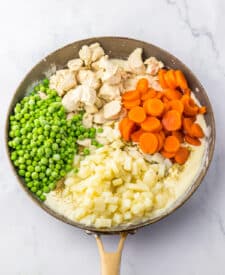 Fresh vegetables including peas, carrots, and potatoes in a mixing bowl