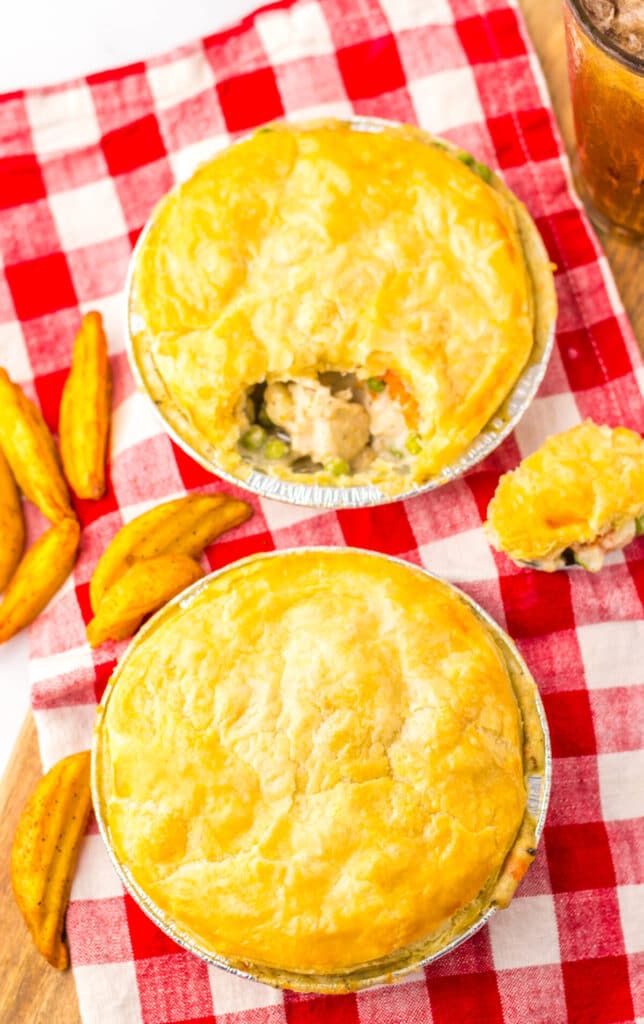 Overhead view of two golden pot pies on a red and white checkered cloth.