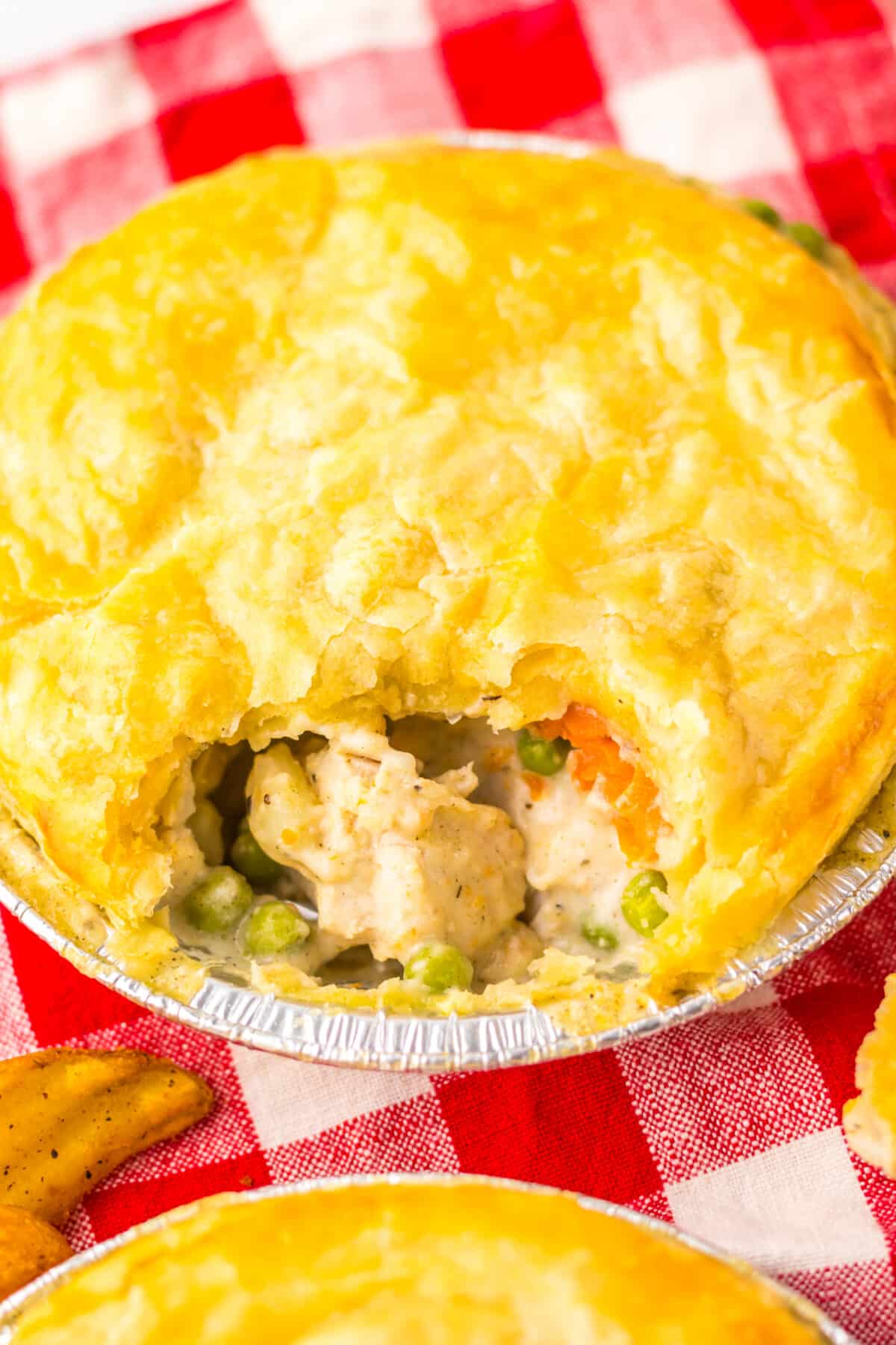 Chicken pot pie with scoop taken out showing creamy filling inside.