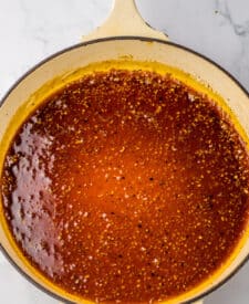 Honey garlic sauce simmering in the skillet, thickening with visible garlic bits throughout.