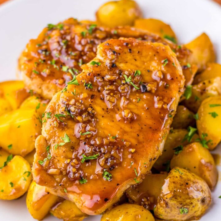 Close-up of juicy glazed pork chops and potatoes, covered in honey garlic sauce and ready to serve.