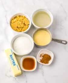 Ingredients for pumpkin spice caramels measured in small bowls on a white background