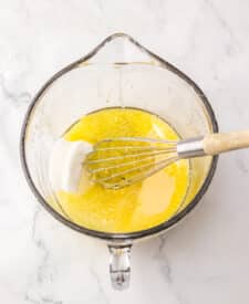 Butter and corn syrup whisked together in a clear glass mixing bowl