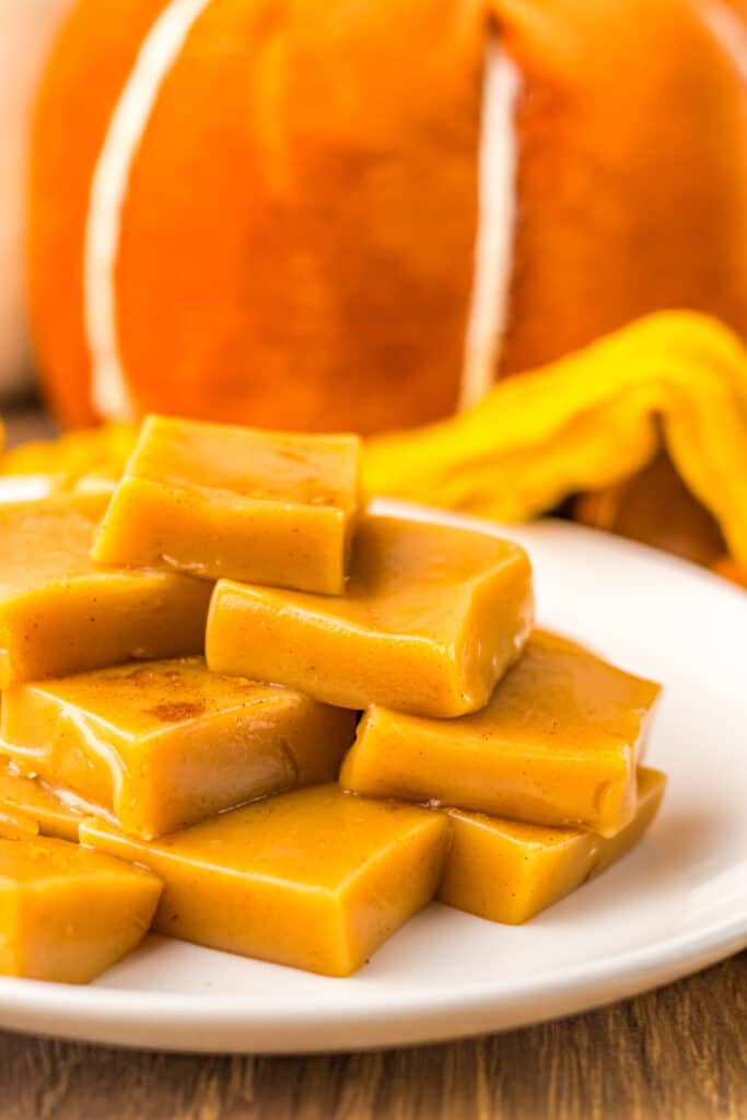 Chewy pumpkin spice caramels displayed on a white dish for fall dessert