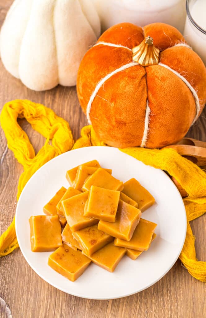 Soft and chewy pumpkin spice caramel candies stacked on a white plate