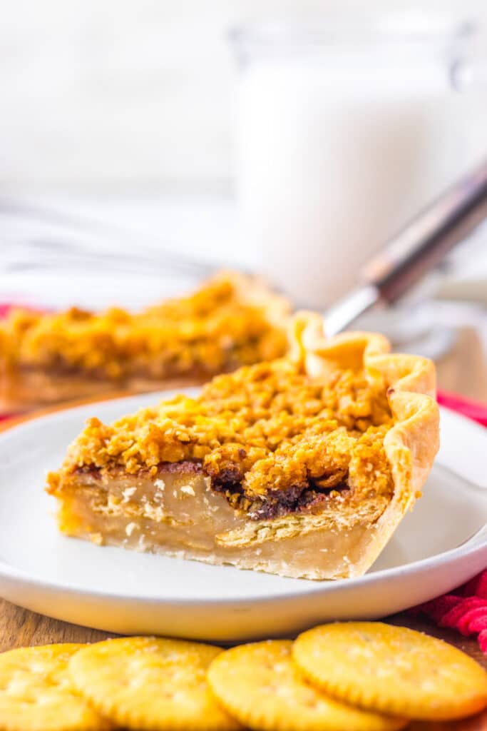 Slice of mock apple pie served on a plate with fork and red napkin in background