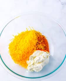 Cream cheese, cheddar, and spices combined in a bowl.
