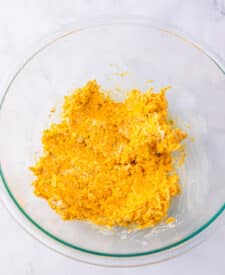 Cream cheese and shredded cheddar cheese mixture in a glass bowl.