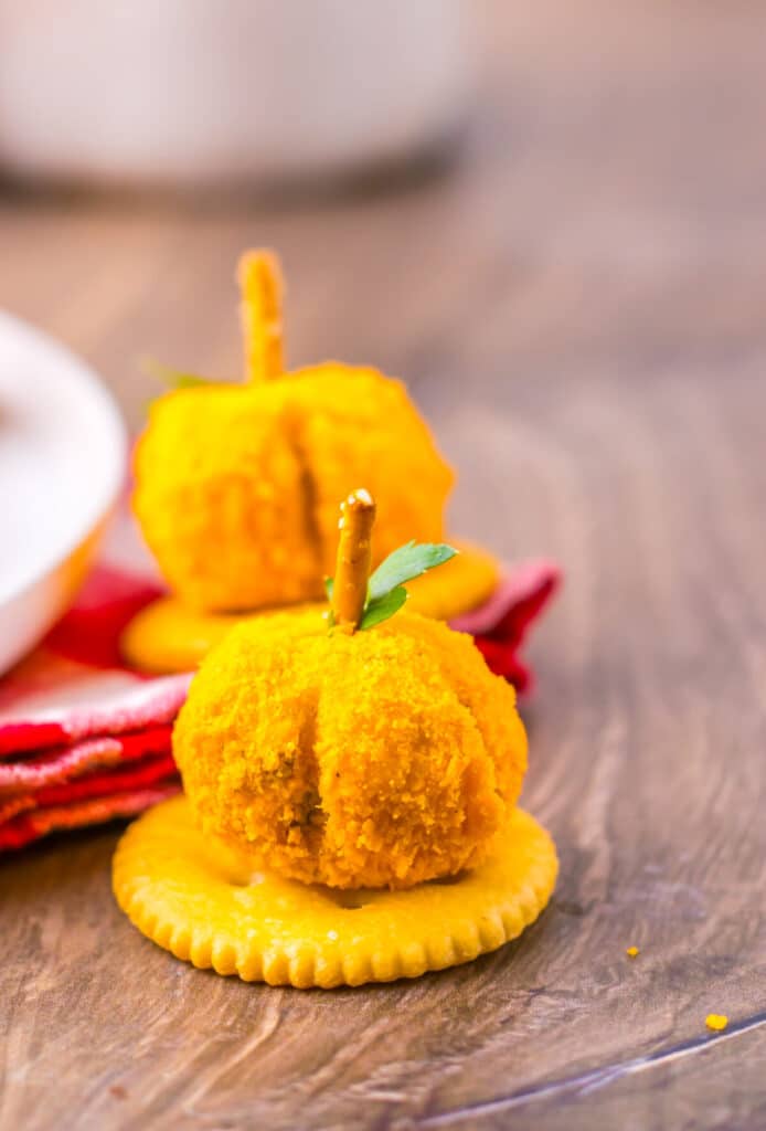 Festive mini pumpkin cheeseballs topped with pretzel stems and parsley leaves.