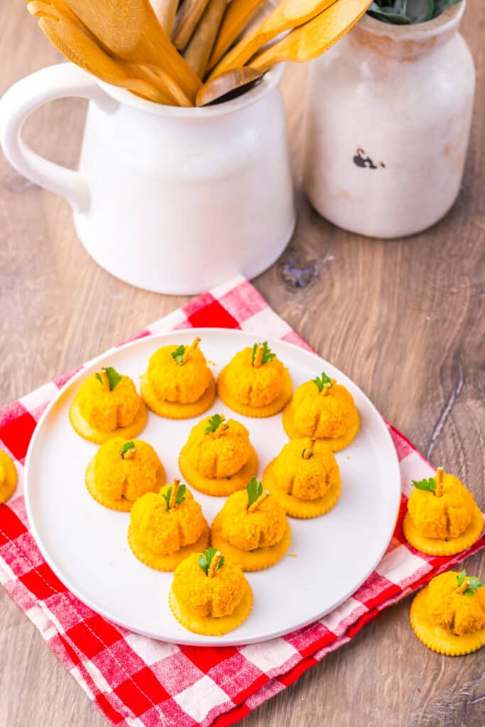 Pumpkin-shaped cheeseballs with pretzel stems arranged on a tray.