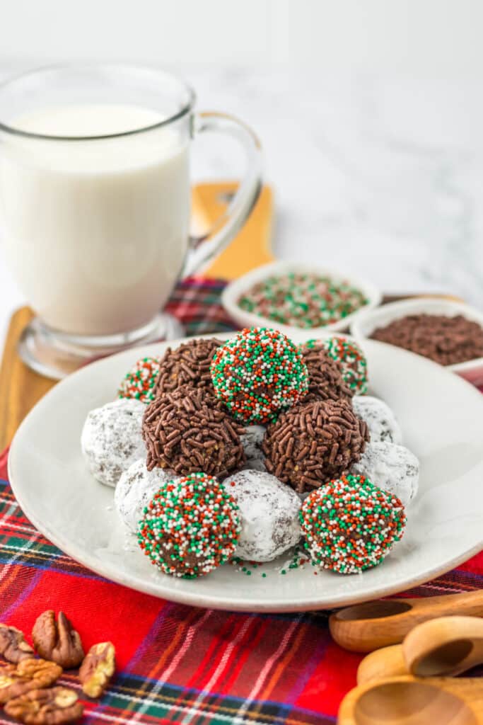 Pecan bourbon balls coated in powdered sugar, chocolate sprinkles, and holiday sprinkles.
