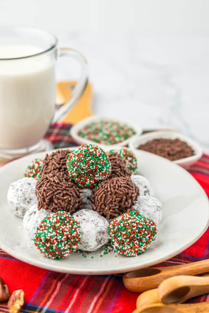 Pecan bourbon balls coated in powdered sugar, chocolate sprinkles, and holiday sprinkles.
