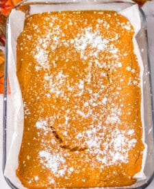 Pumpkin gooey butter bars baked in a 9x13 pan with powdered sugar on top.