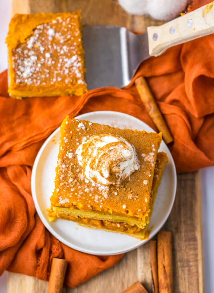9. Pumpkin gooey butter bar slice on a plate topped with whipped cream.