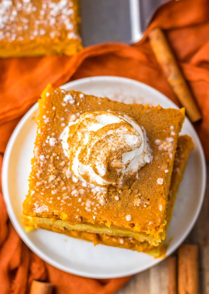 9. Pumpkin gooey butter bar slice on a plate topped with whipped cream.