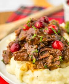 Slow Cooker Cranberry Roast Beef on top of fluffy mashed potatoes with asparagus