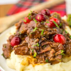 Slow Cooker Cranberry Roast Beef on top of fluffy mashed potatoes with asparagus