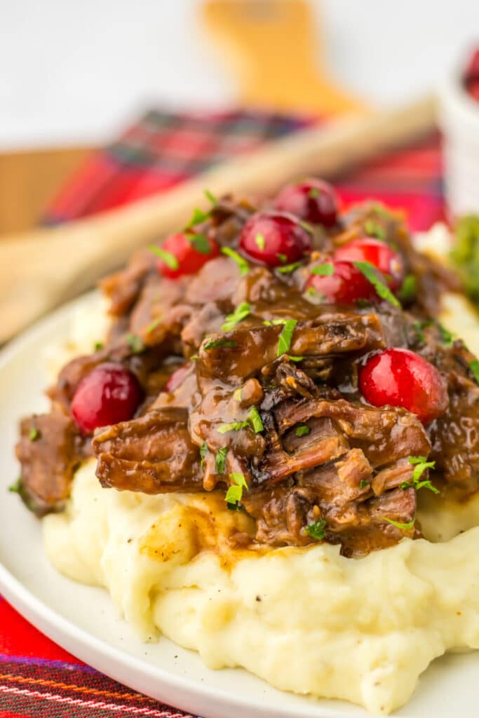 Slow Cooker Cranberry Roast Beef on top of fluffy mashed potatoes with asparagus