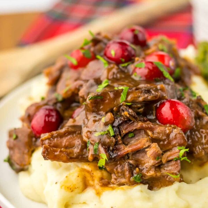 Slow Cooker Cranberry Roast Beef on top of fluffy mashed potatoes with asparagus