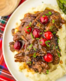 Slow Cooker Cranberry Roast Beef on top of fluffy mashed potatoes with asparagus