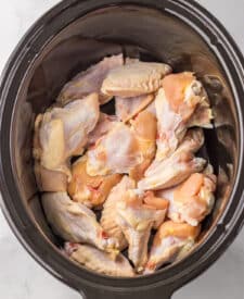 8. Chicken wings in a slow cooker with soy sauce, honey, and garlic nearby.