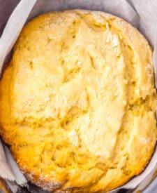 Golden brown slow cooker mock sourdough bread in parchment inside the pot.