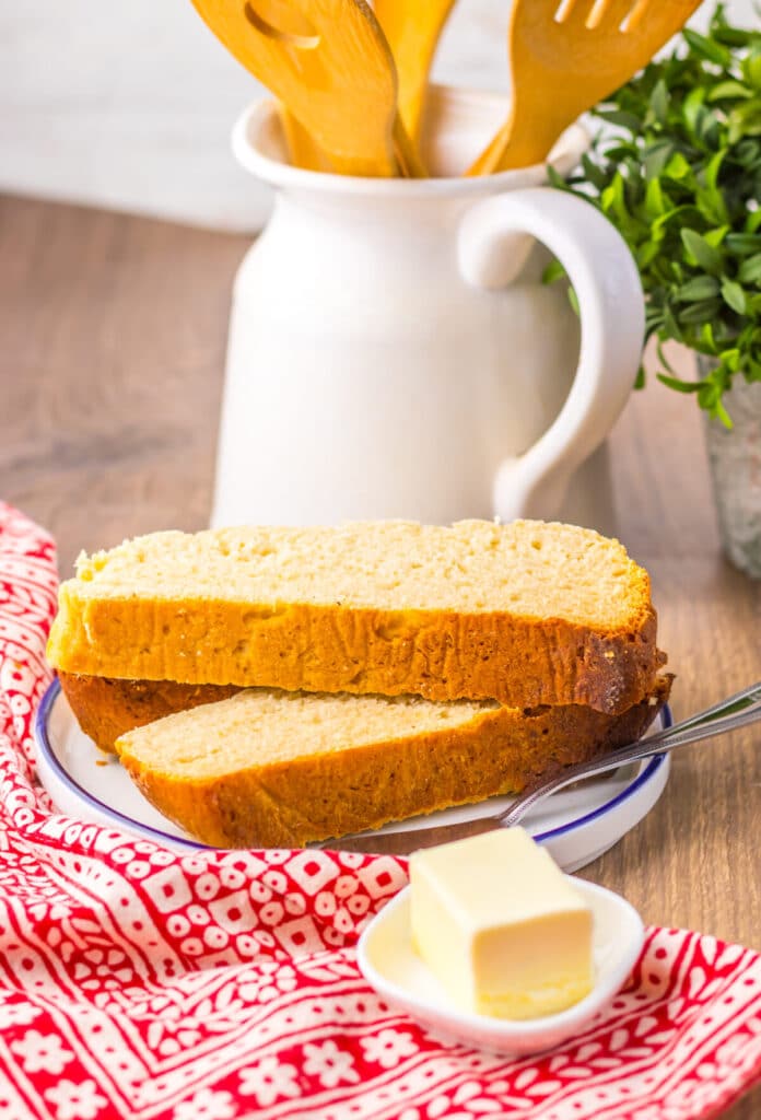 Sliced piece of slow cooker mock sourdough bread on a wooden board with butter knife.