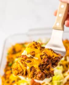 Cheesy taco bubble up bake in a white baking dish with lettuce and tomato topping.