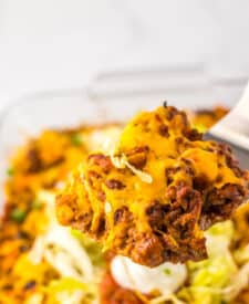 Cheesy taco bubble up bake in a white baking dish with lettuce and tomato topping.