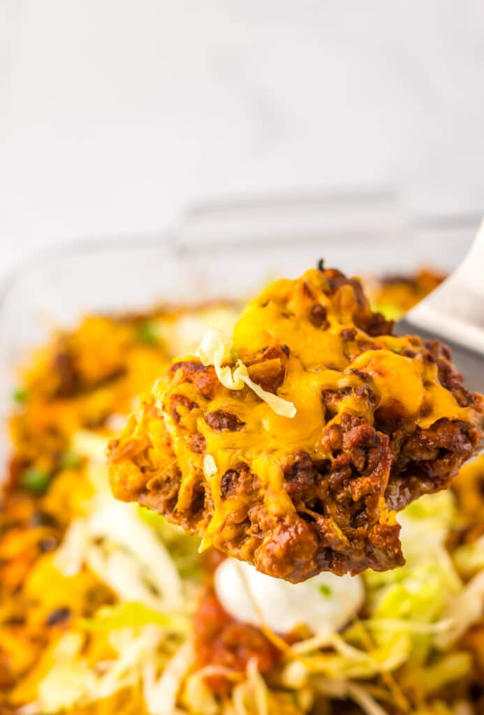 Cheesy taco bubble up bake in a white baking dish with lettuce and tomato topping.