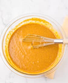 Smooth Apple Butter Pie filling in a glass bowl with a whisk resting inside.