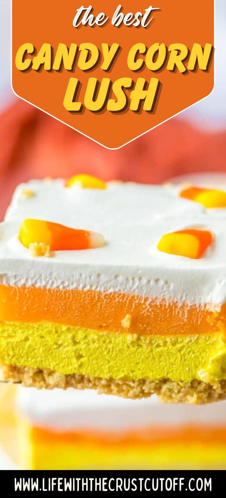Layered candy corn-inspired dessert with yellow, orange, and white creamy layers topped with whipped cream and sprinkles
