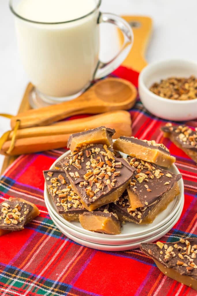 Stacked English toffee pieces glistening with chocolate and almond bits on white plate