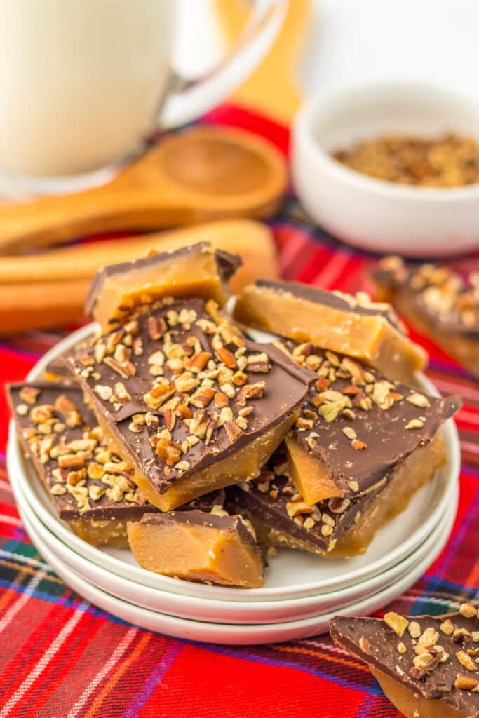 Stacked English toffee pieces glistening with chocolate and almond bits on white plate