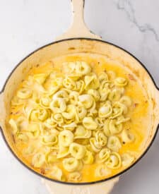 Cooked tortellini tossed in creamy chicken and sun-dried tomato sauce in skillet