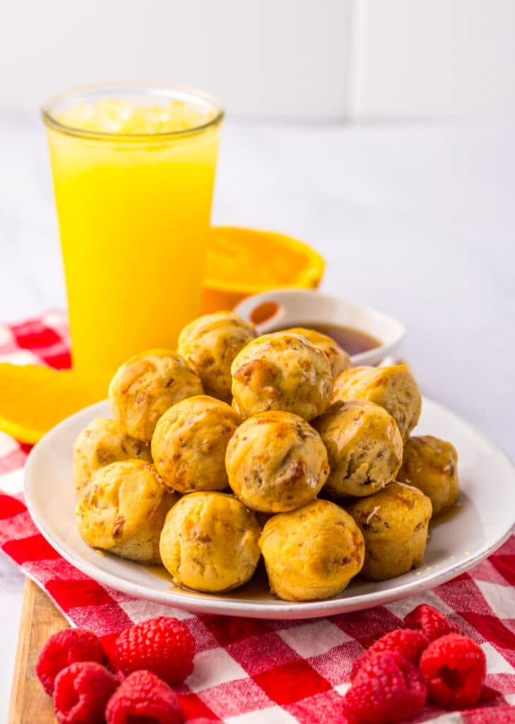 Plate of McGriddle bites beside orange juice on white background
