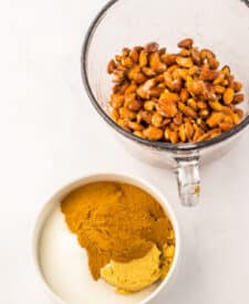 Almonds in a mixing bowl coated with cinnamon sugar mixture.