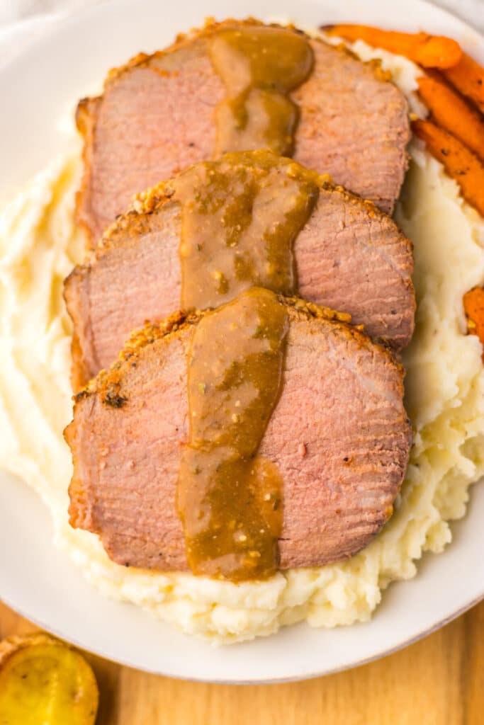 Thin slices of eye of round roast served with mashed potatoes and brown gravy.